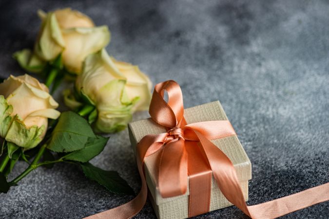 Yellow flower on grey table with small giftbox with copy space