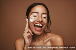 Happy young woman applying cream for vitiligo 5ojBm0