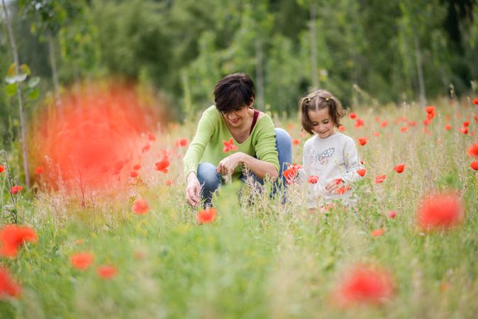 Woman and girl sitting down in poppy field