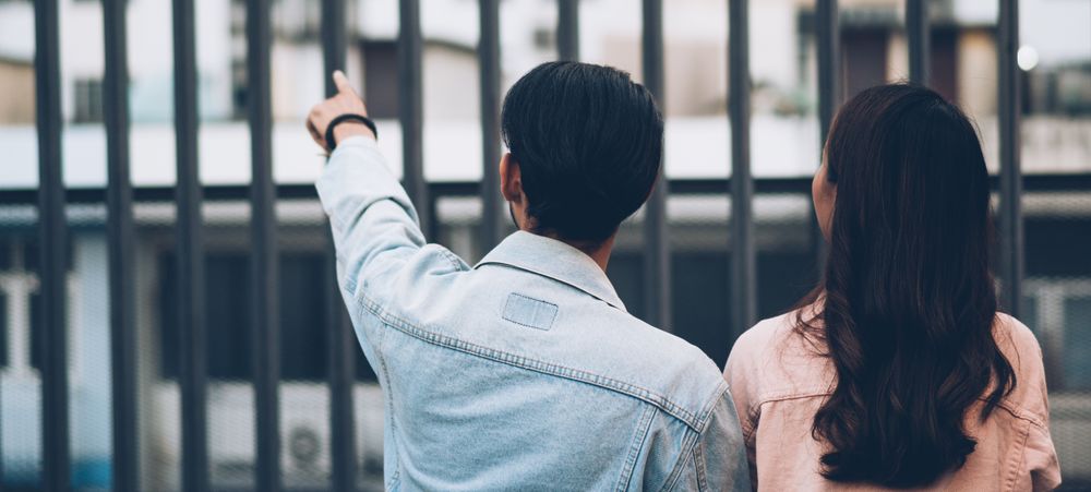 Back of Asian couple on date pointing at something outdoor