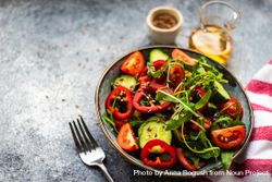 Healthy vegetable salad with organic cucumber, tomatoes, bell pepper, arugula and flax seeds on stone background 0LdrqD