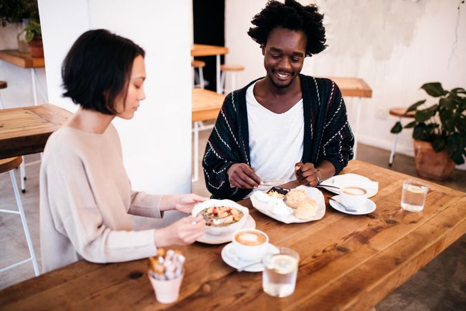 Young woman and man sitting in a restaurant with a light meal and coffee