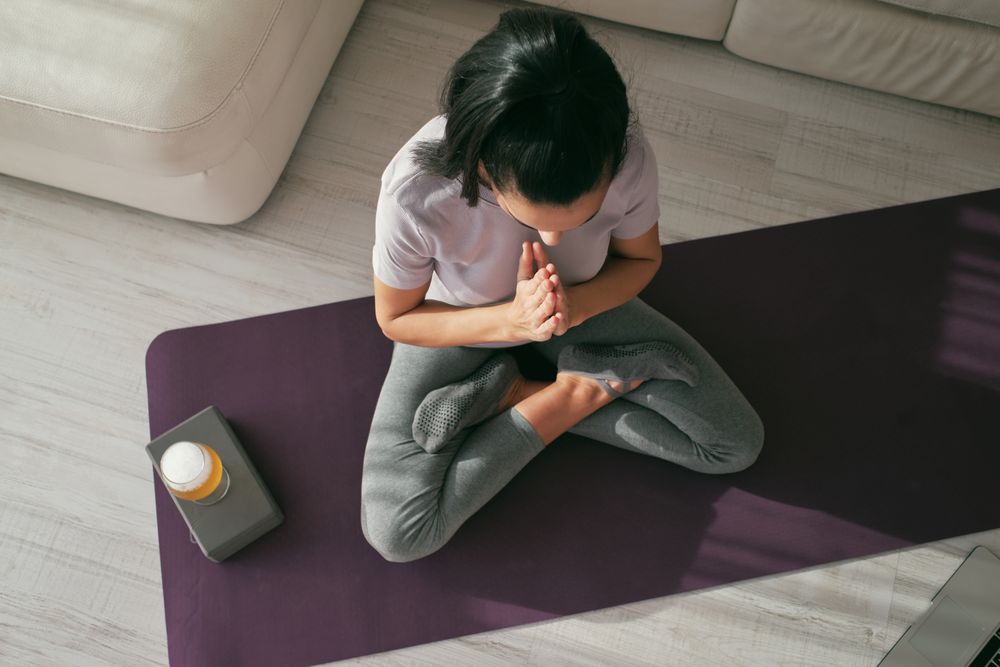 Woman meditating on mat with beer