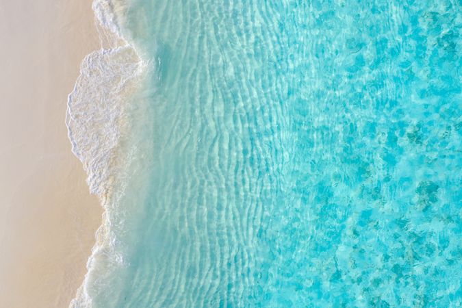 Overhead shot of beautiful clear blue water coming up on a beach