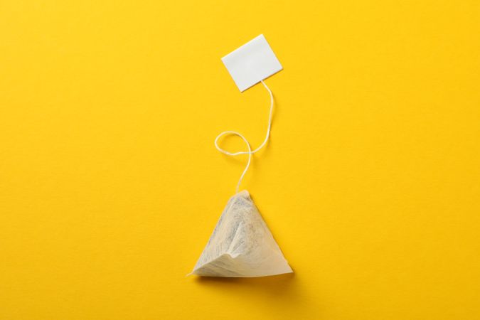 Tea bag with label on yellow background, space for text
