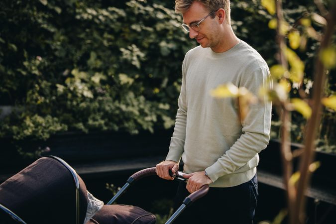 Parent pushing stroller outdoors while on paternity leave