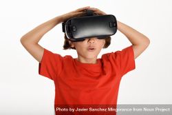 Little girl looking in VR glasses with hands on head 4MLqE5