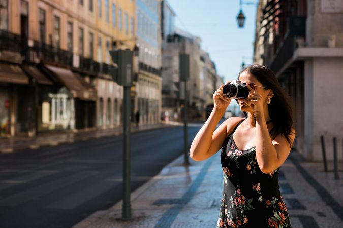 Casual woman taking photo with camera while standing on street