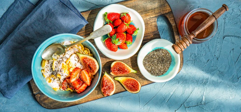 Top view of traditionally healthy breakfast with chia, honey, figs and strawberry on board