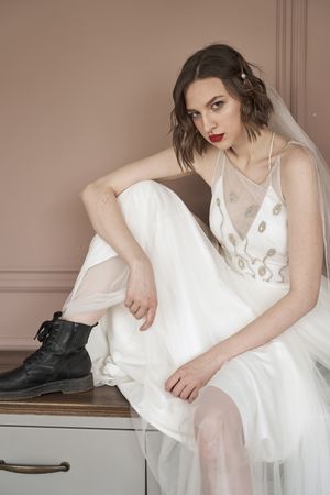 Woman in white dress and military boots looking at camera