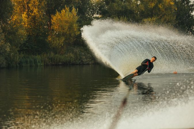 Sporty male using one water ski on calm lake