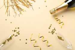 Composition with champagne bottle, glasses and glitter on beige background, copy space