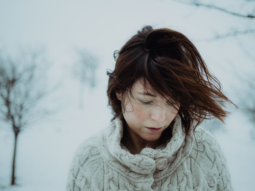 Dreamy woman in sweater against winter landscape
