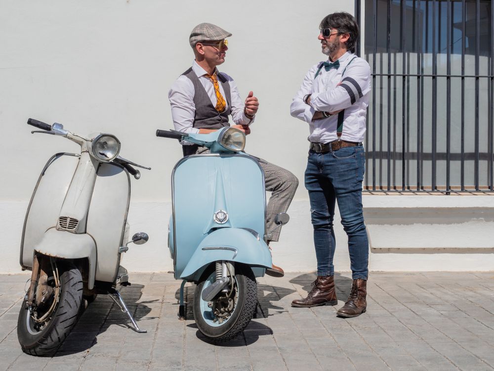 Trendy men chatting near vintage scooters