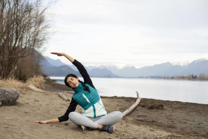 Young female stretching on the lake shore