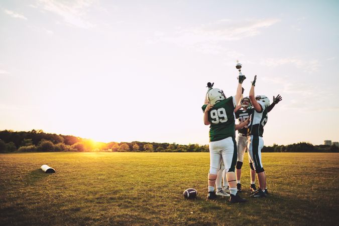Men with arms and trophy in the air celebrating a win on the football field