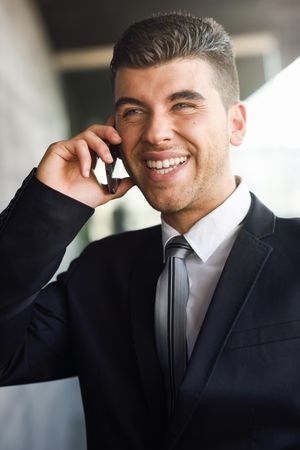 Portrait of smiling man with blue eyes in suit and tie on phone