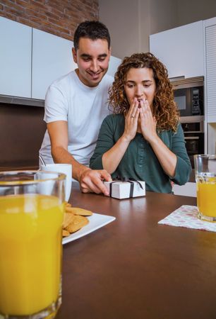 Man giving woman giftbox over breakfast