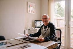 Smiling man considering photos in his home office