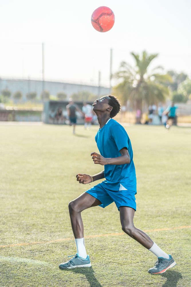 Black teenager jugging football ball on head
