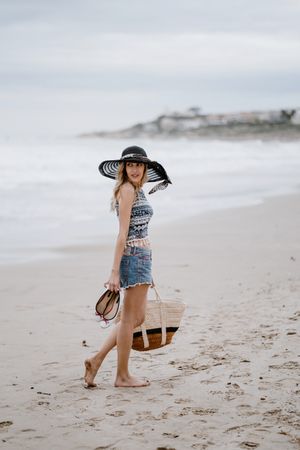 Young female walking barefoot on sandy beach