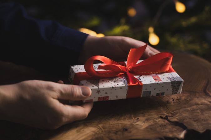 Man holding Christmas gift by wooden table