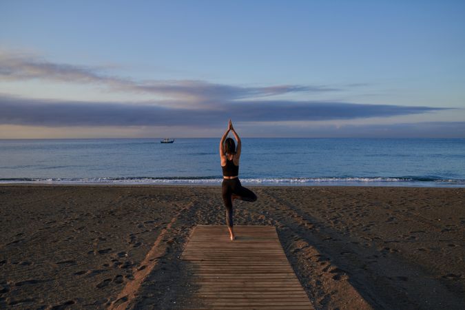 Unrecognizable woman doing tree pose near sea