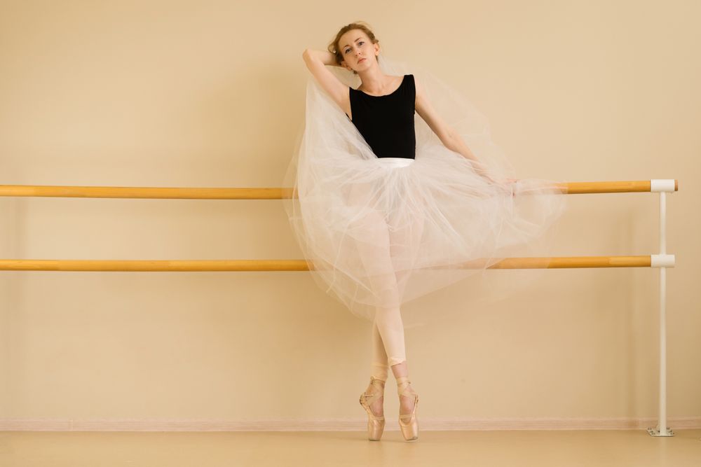 Ballet dancer elegantly displays tutu while posing in dance studio