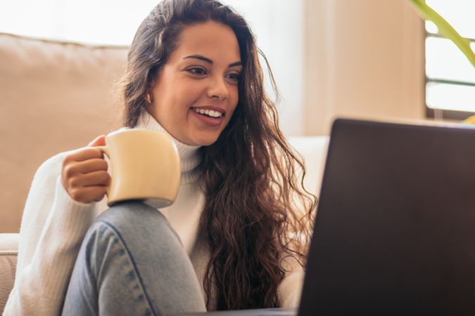 Young Woman Enjoying a Cup of Coffee While Using Laptop"