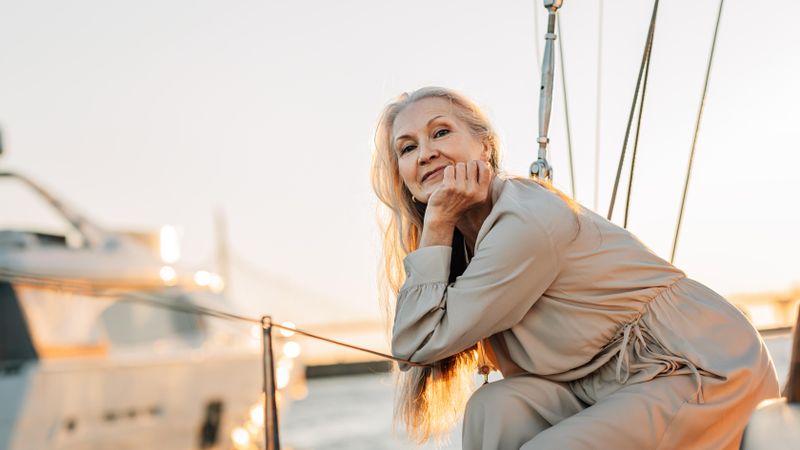 Happy older woman leaning on sailboat railings