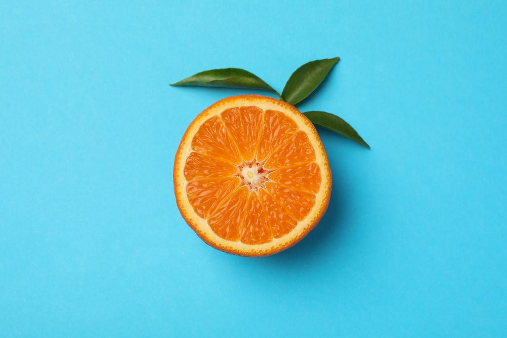 Half of mandarin with leaves on blue background Half of mandarin with leaves on blue background