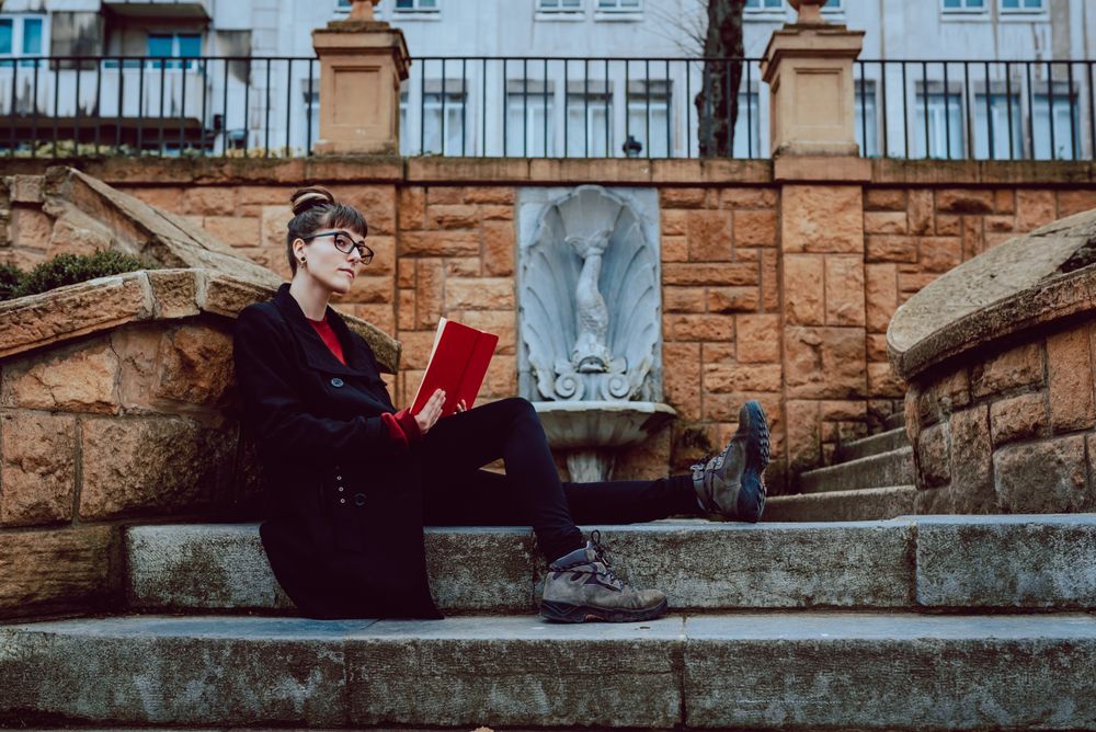 Young woman reading book on steps