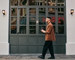 Sideview of young man walking outside tall dark windows
