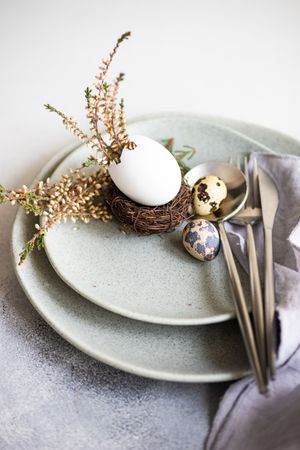 Easter table setting with decorative eggs with nest on ceramic plate with silverware