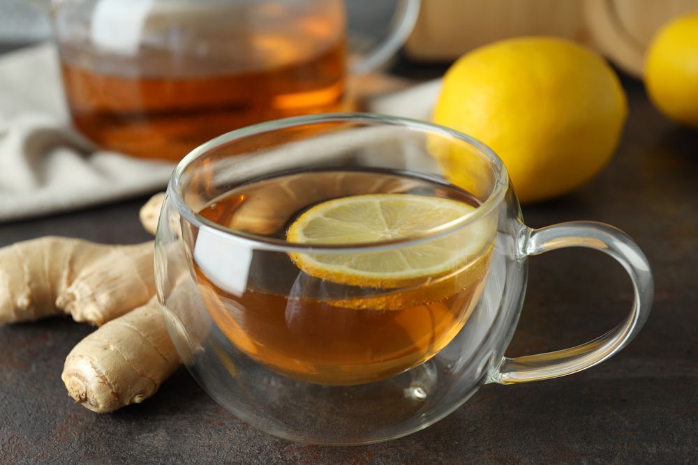 Cup with tea, lemon and ginger on wooden background, close up