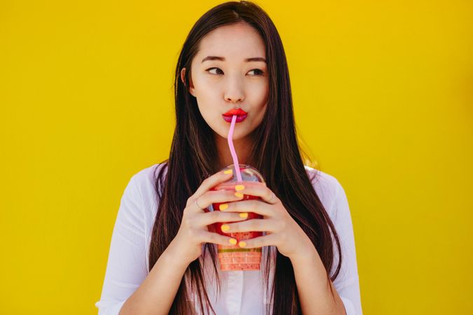 Portrait of a young woman drinking juice from a straw