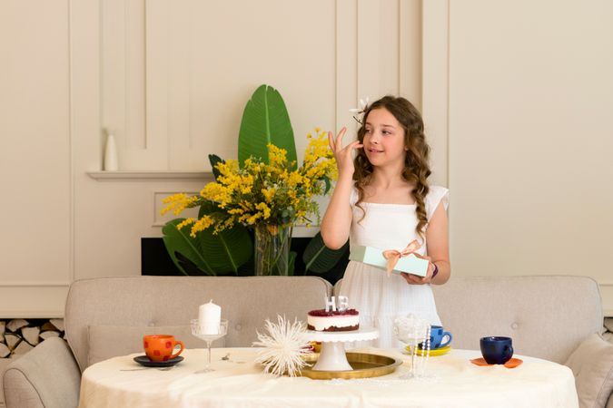 Birthday girl stands at decorated table with cake