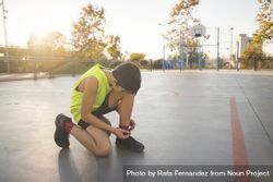 Young man basketball player is tying shoelaces 4OvRR5