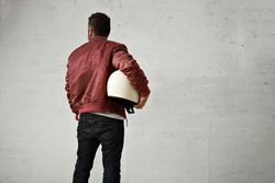 Rearshot of man in dark red leather jacket holding helmet in studio shoot