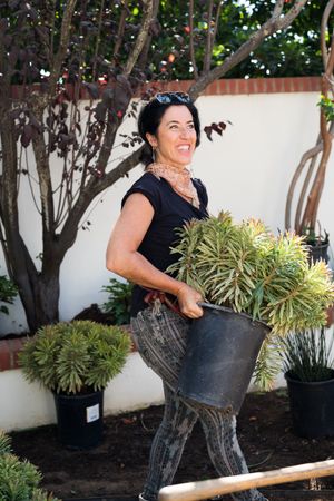 Woman holding a large potted plant in a garden