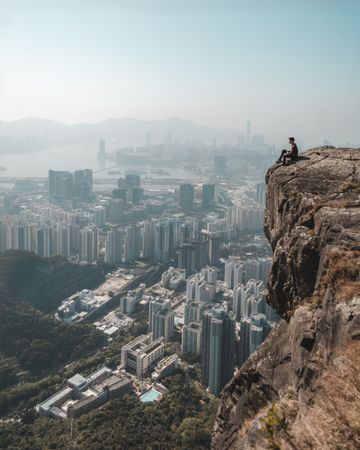 Man sitting on cliff looking down the cityscape of Hong Kong