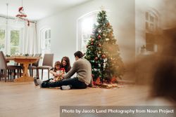 Small family celebrating Christmas by the tree 5pgvxy