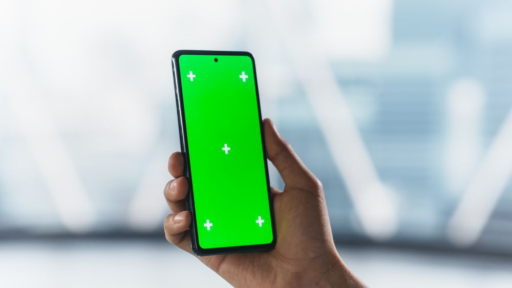 Businessman Checking a Social Network Post on Smartphone with Mock Up Green Screen Chromakey Display. Scrolling, Swiping, Tapping on the Mobile Phone. Concept for Online Services Presentation