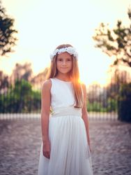 Smiling girl in white dress standing against sunset sky