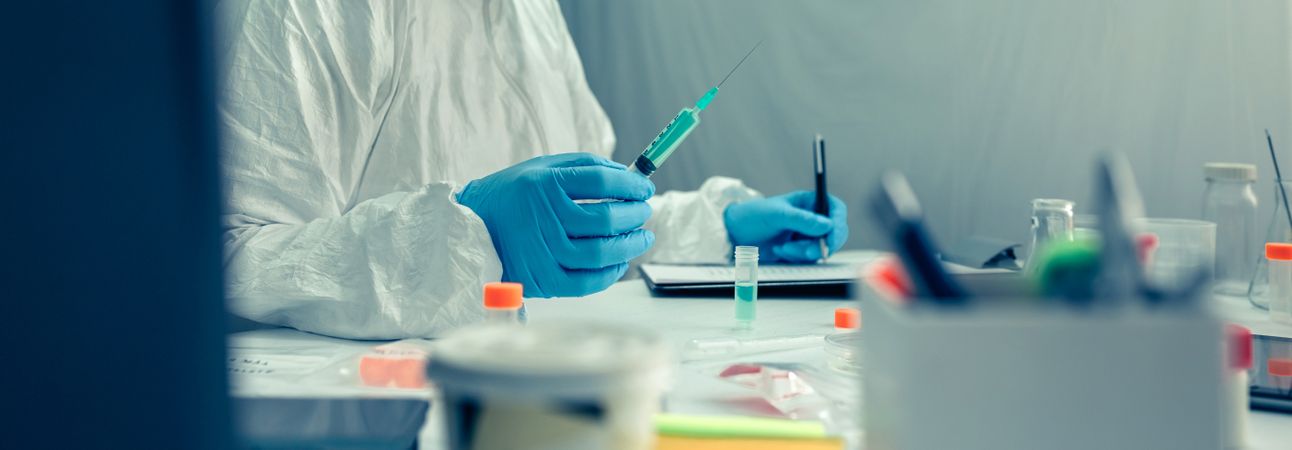 Scientist with protection suit investigating a vaccine in the laboratory
