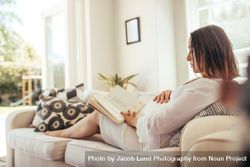 Pregnant woman relaxing on sofa reading  book 41l29N