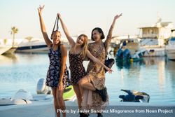 Happy women in summer dresses with arms up on pier bD3ky4