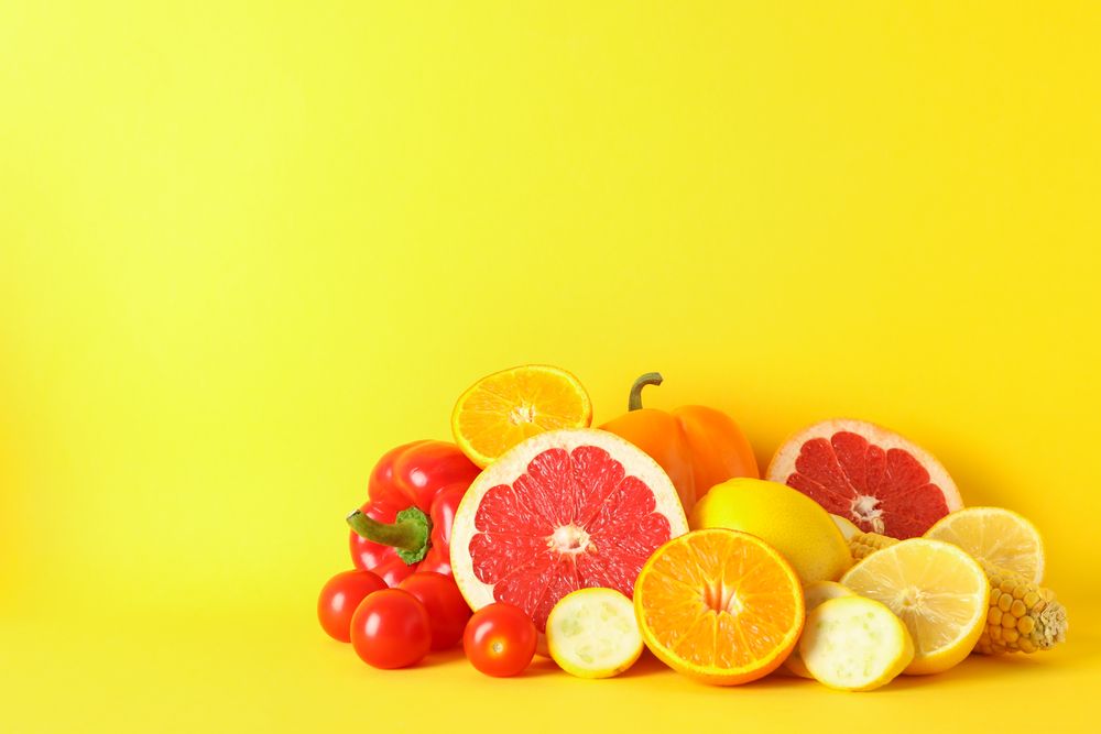 Different vegetables and fruits on yellow background, copy space