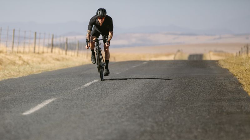 Professional athlete riding bike on countryside highway