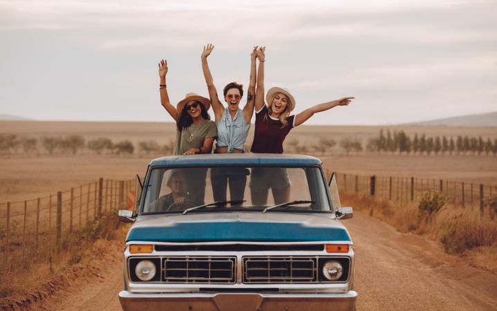 Group of female friends riding in pickup truck having fun on summer day